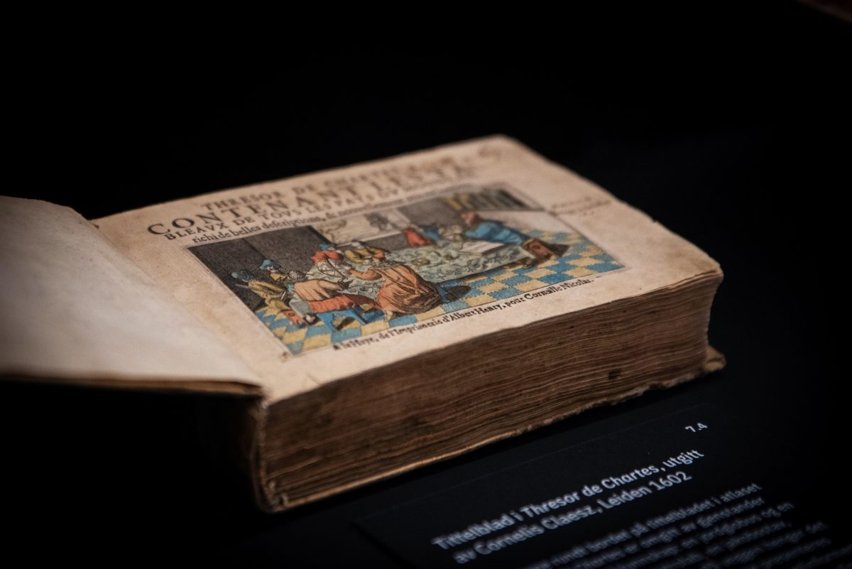 Fotografi. Stor gammel åpnet bok med bilde av fargerik illustrasjon.