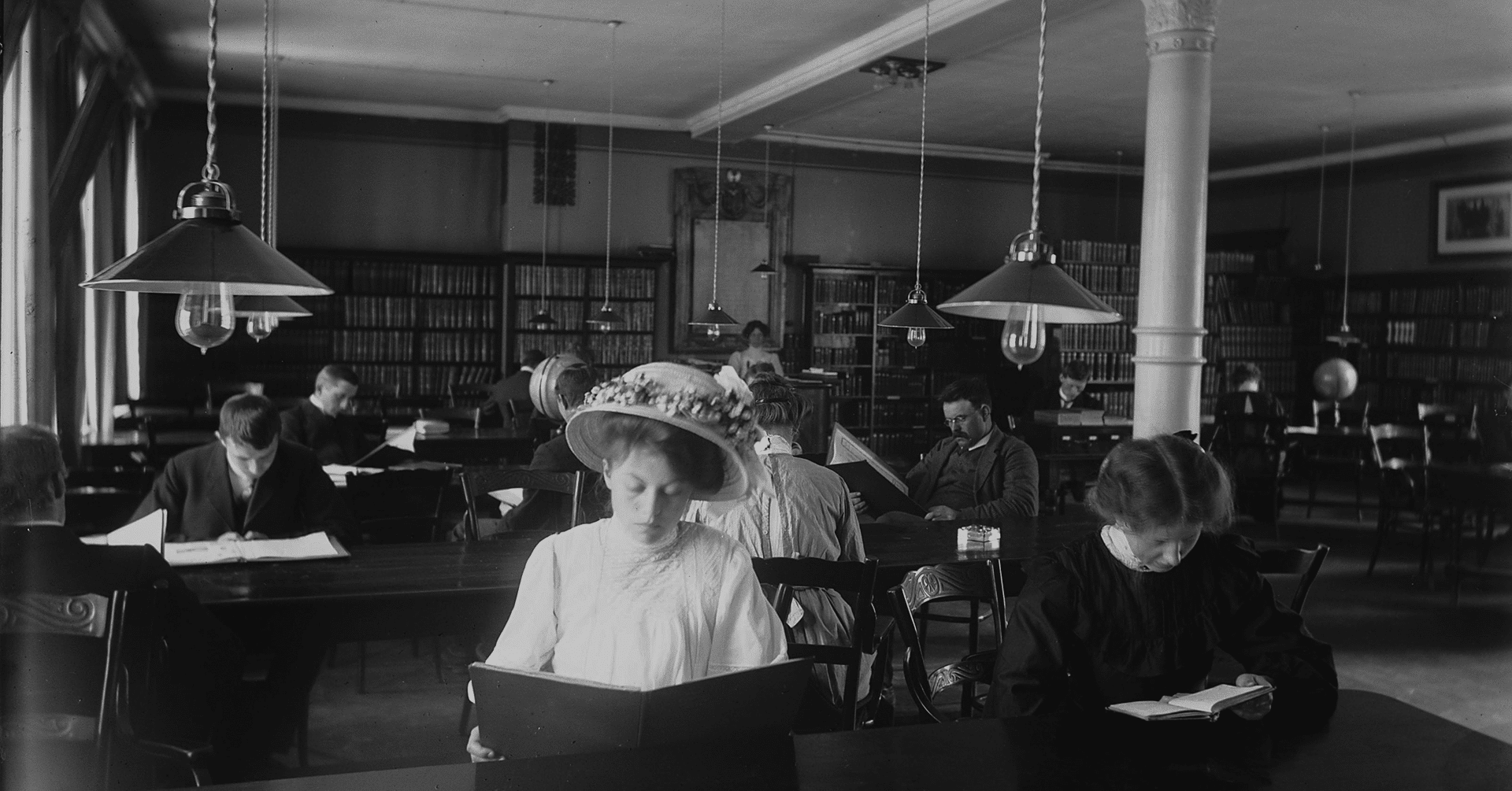 et bilde i svart hvitt som viser folk som sitter stille og leser