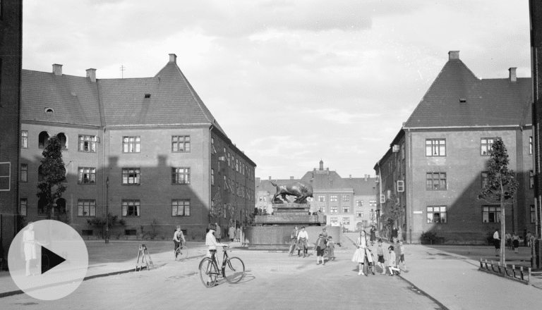 Gatebilde fra Torshov, barn står i gata, hus og fontene i bakgrunnen.
