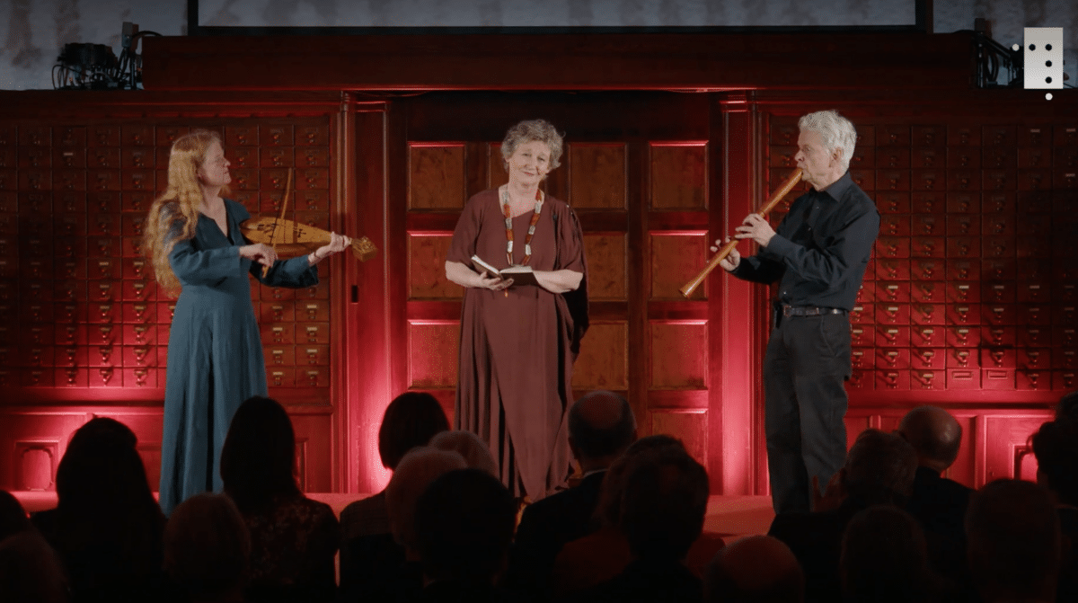 To kvinner og en mann står på en scene og spiller og synger middelaldermusikk. 