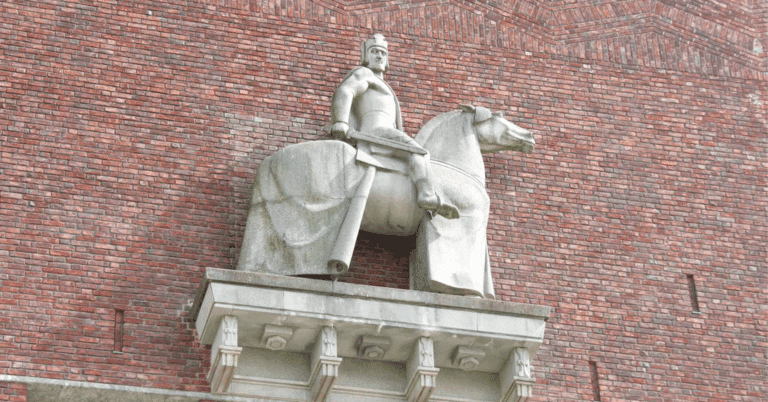 Statue av en mann på hest, plassert på en murvegg