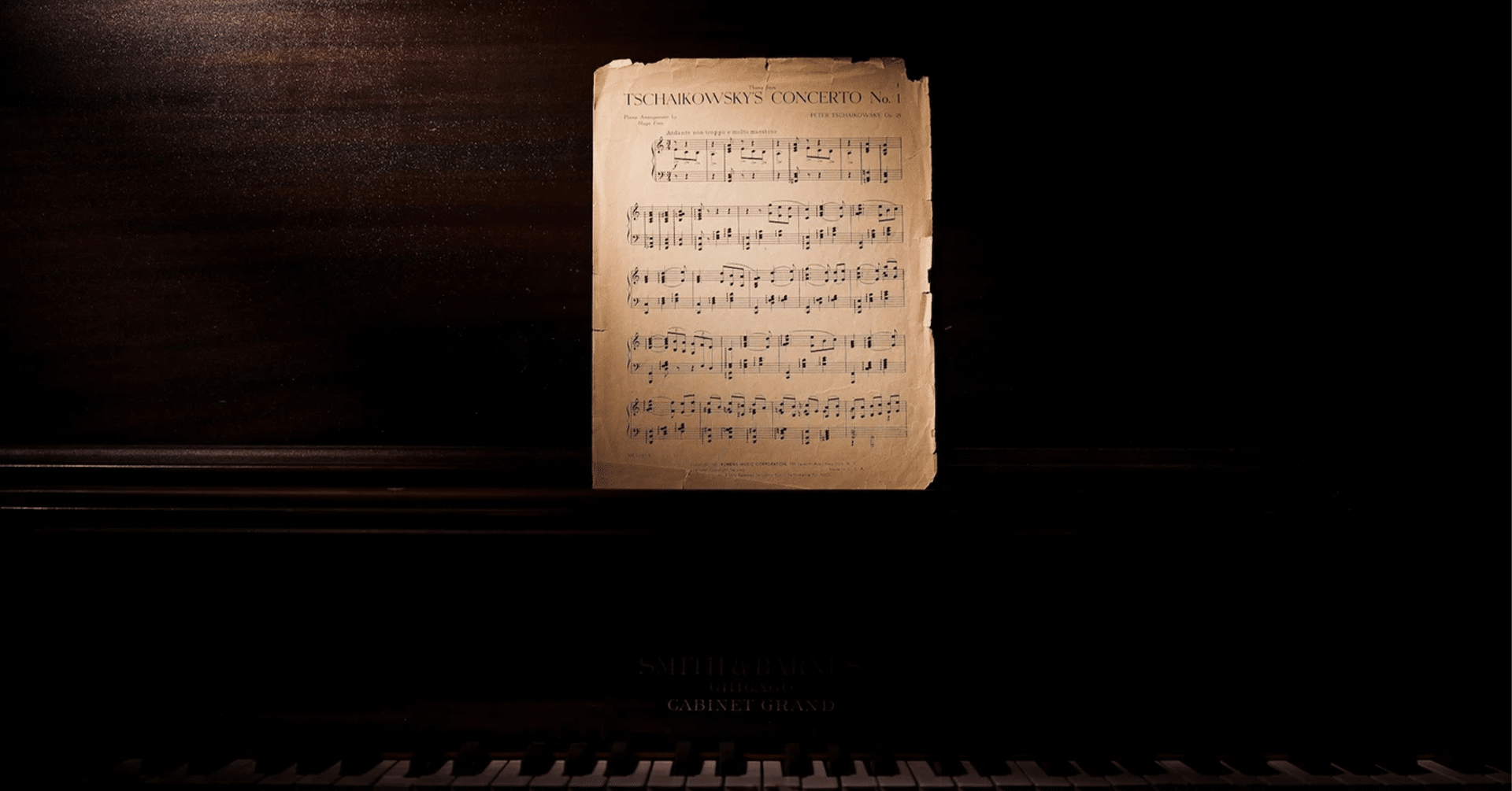 Noter på et slitt ark på et gammelt piano. Rommet er mørkt, men solen treffer notepapiret.