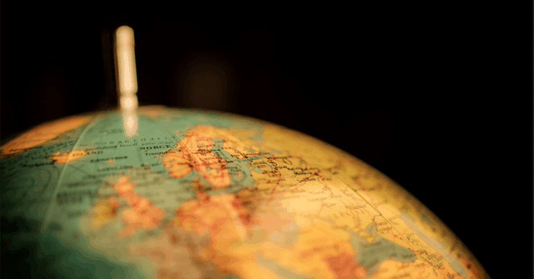Nærbilde av en globus med Norge i fokus. Bildet er varmt belyst mot en mørk bakgrunn.