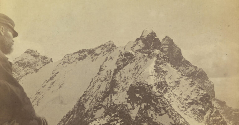 En mann ser ut mot en fjelltopp, dekt av snø