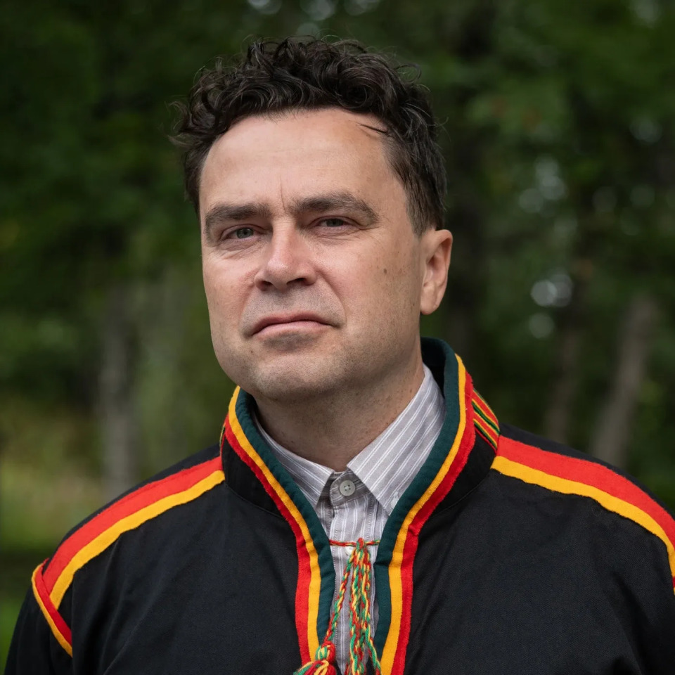 Forfatter Sigbjørn Skåden ser i kameraet. Han er iført svart kofte med gule og rød sømmer.